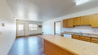 Located at 1820 Dakota Dr N in Fargo, North Dakota, this single-floor home offers a practical and well-organized layout with four bedrooms, three bathrooms, and three closets. The interior is finished with durable wood-look vinyl flooring throughout, complemented by neutral white walls and textured ceilings that give each room a clean, consistent feel.

The combined kitchen and living area serves as the central hub of the home. The kitchen is equipped with warm oak cabinetry, laminate countertops, white appliances including a dishwasher, range, and microwave, and a peninsula that provides additional prep and serving space. The living area is bright and open, featuring a large sliding window that brings in natural light and a direct-entry door for convenient access.

Each of the four bedrooms is well-sized, with the primary bedroom offering a notably generous footprint. Bedrooms feature windows for natural light, baseboard heating, and access to closets — including walk-in closets fitted with wire shelving systems for organized storage. The three bathrooms are consistently finished with oak vanities, laminate countertops, and large mirrors. Baseboard heating is present throughout the home, ensuring efficient warmth during Fargo's cold winters. The overall layout is straightforward and functional, suited for shared or family living.