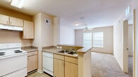 Located at 7400 Hogan Rd in Jacksonville, FL, this one-bedroom, one-bathroom residence offers a practical and well-organized single-floor layout. The kitchen is outfitted with light maple cabinetry, laminate countertops, a coil-burner electric range, a dishwasher, and a peninsula with a double-basin sink that opens directly to the living area — creating a connected, functional flow between cooking and living spaces. The living room benefits from large windows that bring in generous natural light and is equipped with a ceiling fan for year-round comfort. Flooring transitions from wood-look vinyl in the kitchen to plush carpet throughout the living and bedroom areas. The spacious primary bedroom features its own ceiling fan, a window with blinds, and direct access to a generous walk-in closet lined with wire shelving on multiple walls, offering ample storage. The bathroom is designed with accessibility in mind, featuring grab bars, a single-sink vanity with light maple cabinetry, and wood-look vinyl flooring. Neutral warm tones and a clean, understated palette carry throughout the entire residence, creating a calm and cohesive atmosphere well-suited for comfortable everyday living.