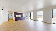 Located at 598 W Main St in Charlottesville, Virginia, this contemporary residence offers a thoughtfully designed one-bedroom, two-bathroom layout spread across a single expansive floor. The open-concept living and kitchen area is the centerpiece of the home, characterized by light hardwood flooring, crisp white walls, and recessed lighting throughout. A striking kitchen anchors the space, featuring a large waterfall-edge island with a built-in sink, rich dark wood cabinetry extending to the ceiling, a clean white backsplash, and stainless steel appliances. The living area is generously proportioned, bathed in abundant natural light through oversized floor-to-ceiling windows with sleek black frames that frame panoramic views of the Charlottesville skyline and surrounding Blue Ridge landscape. The bedroom is a well-sized, serene retreat with warm hardwood floors and access to a walk-in closet outfitted with wire shelving. Two modern bathrooms serve the home, one featuring a glass-enclosed walk-in shower, dark accent wall, and a floating dark wood vanity with matte black fixtures. The overall aesthetic is clean, contemporary, and urban, offering a refined living experience in the heart of downtown Charlottesville.