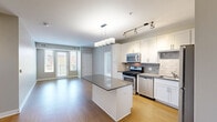 Located at 205 W Touhy Ave in Park Ridge, IL, this well-appointed 4-bedroom, 2-bathroom residence offers a thoughtfully designed single-floor layout. The open-concept kitchen and living area serves as the heart of the home, showcasing warm hardwood flooring, white shaker cabinetry, a gray quartz-topped center island, subway tile backsplash, and a full suite of stainless steel appliances including a gas range, microwave, dishwasher, and refrigerator. Pendant lighting above the island adds a modern touch. The living area flows naturally toward a glass door that opens onto a private balcony, bringing in generous natural light and outdoor views of the brick building exterior. The four bedrooms feature neutral carpet, ceiling fans, and ample closet space, including a walk-in closet with wire shelving. The spacious primary bedroom provides a comfortable retreat. Two bathrooms serve the unit: one features a tiled tub-shower combo with hardwood-style flooring, while the second offers a sleek vanity with a dark countertop, large-format tile flooring, and a mirror. Neutral gray walls and clean white trim throughout give the entire space a cohesive, modern aesthetic.