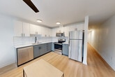 Located at 4730 University Way, this efficiently designed 2-bedroom, 1-bathroom unit offers a clean, modern aesthetic throughout its single-floor layout. Light hardwood flooring runs continuously through the space, creating a cohesive and bright atmosphere complemented by crisp white walls and flush ceiling lighting.

The great room flows directly into a well-appointed kitchen featuring stainless steel appliances — including a refrigerator, electric range, and dishwasher — paired with two-tone cabinetry in white and slate blue, white subway tile backsplash, and a deep utility sink. A ceiling fan adds comfort to the living area.

A long, bright hallway connects the main living space to the private rooms, lined with clean white walls and classic panel doors. Both bedrooms are cozy and functional, each fitted with a ceiling light fixture and closet storage — including a double-door closet in the primary bedroom. The second bedroom accommodates a twin-sized bed alongside a built-in desk area, ideal for work or study.

The combined bathroom and laundry room is finished in a clean, minimalist style with light wood-look flooring, a full soaking tub with shower, matte black fixtures and hardware, and open wall-mounted shelving for storage. Two dedicated closets provide additional storage throughout the unit.