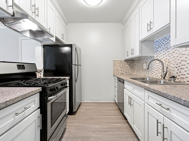 Custom tiled kitchen with stainless steel fridge, sink, and oven. - Rose North