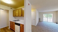 This single-floor unit offers five bedrooms and two full bathrooms, making it a practical and spacious option for shared or multi-occupant living. The layout is efficiently organized, with two hallways connecting the various rooms throughout the unit.

The kitchen features warm oak cabinetry, white countertops, a stainless steel sink, a dishwasher, and a refrigerator, all set atop durable wood-look flooring. It opens conveniently toward the main living areas, providing an accessible and functional cooking space.

The living room is generously proportioned with soft carpeting and a sliding glass door that opens onto a private balcony, allowing natural light to fill the space and offering pleasant outdoor views.

Each of the five bedrooms is finished with neutral-toned carpet and light-colored walls, creating a clean and versatile environment. Several bedrooms feature windows with blinds that bring in natural light and exterior views. The primary bedroom includes access to a dedicated closet for added storage.

The two bathrooms are well-appointed with wood-look flooring, oak vanity cabinetry, and white fixtures. One bathroom includes a full tub-shower combination with grab bars, while the second features a walk-in shower with a built-in seat and grab bar, reflecting practical, accessibility-conscious design throughout the unit.