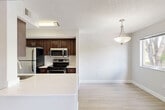 Located at 17240 NW 64th Ave in Hialeah, FL, this one-bedroom, one-bathroom unit offers a well-designed, single-floor layout that maximizes its compact footprint. The open-concept living area features light wood-style flooring throughout and a textured ceiling, creating a bright and cohesive feel. A ceiling fan with integrated lighting anchors the living space, which benefits from natural light streaming through a sliding glass door that leads to a private balcony with tree-lined views.

The kitchen is efficiently designed with rich dark wood cabinetry, white countertops, and a full suite of stainless steel appliances including a refrigerator, electric range, and over-the-range microwave. A peninsula counter extends into the living area, providing a casual dining or prep surface and reinforcing the open flow between spaces.

The spacious primary bedroom accommodates generous furnishings and includes a ceiling fan, a large window with leafy outdoor views, and access to a dedicated closet. The bathroom features a clean, white tiled tub-and-shower combination, a dark wood vanity with a white countertop, and light tile flooring. A utility room rounds out the functional layout, adding practical storage and service space.