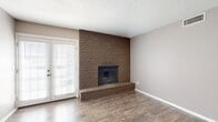 This well-appointed one-bedroom, one-bathroom residence offers a thoughtfully organized single-floor layout. The living room serves as the centerpiece of the home, anchored by a striking floor-to-ceiling brick fireplace with a raised hearth that adds warmth and character to the space. Wood-look flooring runs throughout the living and kitchen areas, while a glass-paneled door brings in natural light and provides outdoor access.

The galley-style kitchen is efficiently designed with rich dark brown cabinetry offering generous storage, granite-look countertops, a double sink, and standard appliances including an electric range and refrigerator. A ceiling fan and window keep the adjoining dining area bright and comfortable.

The bedroom is a comfortable retreat featuring plush carpeting, a ceiling fan, and a window that allows natural light to filter in. A bifold closet door opens to a well-organized built-in shelving and hanging system, maximizing storage efficiency. An additional carpeted closet provides even more storage space.

The bathroom is clean and functional, featuring a full tub-shower combo with white tile surround, wood-look flooring, and a vanity with granite-look countertop. A hallway connects the rooms seamlessly, completing this practical and comfortable single-level layout with a textured ceiling found throughout.