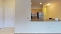 This single-story residence at 13230 Steelecroft Pkwy in Charlotte, NC presents a functional, well-organized layout designed for everyday comfort. The kitchen serves as a central feature, showcasing warm honey-toned cabinetry, dark granite-style countertops, and stainless steel appliances including a refrigerator, range, and built-in microwave. A breakfast bar with matching countertop connects the kitchen to the adjacent living area, creating an open, sociable flow between spaces. The kitchen also features hardwood-style flooring and a pantry door, adding practical storage.

The living area is carpeted and bathed in natural light through large windows fitted with blinds, offering outdoor views of the surrounding greenery. A glass-paneled exterior door provides additional light and direct outdoor access. Ceiling fans in the main living spaces enhance comfort throughout the unit.

The bedrooms are spacious and carpeted, each benefiting from natural light through windows with blinds. The bathroom features wood-style flooring, a white vanity with dark countertop, a multi-bulb vanity light strip, a large mirror, and ample closet storage with paneled doors. The overall aesthetic is clean and neutral, with light-toned walls throughout providing a bright, welcoming ambiance.