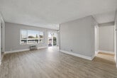 This thoughtfully designed 2-bedroom, 2-bathroom unit spans a single floor, offering a functional and comfortable layout. The living room serves as the heart of the space, finished with light-toned hardwood-style flooring and a textured ceiling. Large windows and a sliding glass door flood the room with natural light and provide direct access to a private outdoor balcony, where views of surrounding palm trees and the neighborhood can be enjoyed. A ceiling fan adds to the comfort of this welcoming area.

The galley-style kitchen is well-equipped, featuring white shaker cabinetry, quartz countertops, a grey subway tile backsplash, and stainless steel appliances including a gas range, dishwasher, and refrigerator. A skylight brightens the space, making it feel open and airy.

Both bedrooms are carpeted and offer a quiet, cozy atmosphere, with the primary bedroom providing a closet with mirrored sliding doors and ample space. The second bedroom similarly features a closet with organized storage.

The two bathrooms are clean and modern, with one showcasing a white vanity with quartz countertops and brushed nickel hardware, alongside a separate water closet with a full bathtub and shower. Light wood-look tile flooring ties the bathrooms together seamlessly. A dedicated entrance completes this well-organized layout.