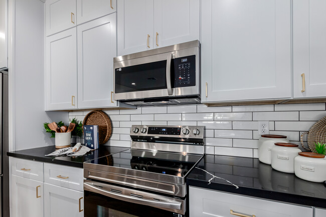 Cocina con encimeras de mármol blanco y negro y gabinetes blancos. - The CJ Luxury Townhomes