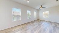 Located at 5040 Camino San Fermin in San Diego, CA, this well-appointed two-story home offers three bedrooms, two bathrooms, and a thoughtfully designed layout across two floors. The main living level hosts an open-plan dining and living area filled with natural light from multiple windows, complemented by light-toned hardwood-style flooring and a ceiling fan with integrated lighting. The modern kitchen is a standout feature, boasting rich dark cabinetry, stainless steel appliances including a range, microwave, dishwasher, and wine cooler, light quartz countertops, and a stylish mosaic tile backsplash. The three bedrooms are carpeted for comfort, each offering closet access — with several walk-in closets featuring multi-tier wire shelving systems. The primary bedroom is generously sized and bathed in natural light through multiple windows. The bathrooms are finished with large-format light tile flooring, glass-enclosed showers with tile surround, and dark-toned vanities with white countertops. Carpeted staircases with white railings connect the floors. Additional features include a laundry room, utility room, two balconies, and an attached garage with an automatic opener.