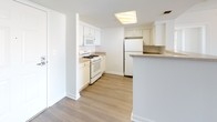 This single-floor residence offers a well-organized layout with a clean, neutral aesthetic carried consistently throughout. The open living area is a highlight, featuring wood-style plank flooring, a built-in fireplace, and a large window that draws in natural light while offering exterior views. Track lighting overhead adds a functional yet contemporary touch to this versatile space.

The kitchen is designed for practicality, outfitted with white cabinetry, a gas range, built-in microwave, full-size refrigerator, and a peninsula that doubles as a breakfast bar. A skylight-style ceiling fixture brightens the workspace, and wood-style flooring extends seamlessly from the kitchen into the adjacent living area.

The bedrooms are carpeted in a warm beige tone, providing comfort underfoot. One bedroom features a distinctive curved bay window that floods the room with light, while another includes a walk-in closet accessible through panel doors. The textured ceilings are consistent throughout the carpeted rooms.

A tiled hallway connects the living spaces to the bathroom, which is finished in crisp white tile with a full soaking tub and shower combination. The overall ambiance is bright, clean, and move-in ready, with a cohesive light gray and white color scheme unifying every room.