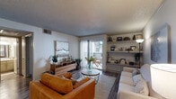 This single-floor residence is thoughtfully laid out to maximize comfort and functionality throughout. The living room serves as the heart of the home, featuring wood-look flooring, a textured ceiling, and built-in shelving that provides both storage and display space. A sliding glass door floods the room with natural light and opens to a private outdoor balcony, creating a seamless indoor-outdoor connection. The adjacent dining area is an intimate nook accented by decorative wall art and a round wood dining table, offering a cozy setting for meals. The kitchen is well-equipped with granite-style countertops, gray cabinetry, a tile backsplash, and black appliances including an electric range with an overhead stainless steel microwave. A separate laundry area is conveniently accessible from the kitchen. The bedroom is a tranquil retreat with wood-look flooring, a ceiling fan, and a window that allows soft natural light to filter in. The full bathroom features a wide vanity with granite-style countertops, ample cabinetry, a large mirror with overhead lighting, and a tub-shower combination. Consistent wood-look flooring and a neutral color palette tie the entire space together in a cohesive, modern aesthetic.