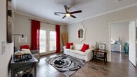 This single-floor residence offers a thoughtfully designed layout that balances comfort and functionality. The living room serves as the heart of the home, featuring rich hardwood-style flooring, crown molding, and a ceiling fan overhead. A set of French doors floods the space with natural light and provides outdoor access, framed by bold red curtains that add a striking pop of color. The galley-style kitchen is both stylish and practical, showcasing dark cabinetry with silver hardware, stainless steel appliances including a refrigerator, range, and built-in microwave, and a decorative mosaic tile backsplash. The kitchen opens seamlessly into a dedicated dining area, creating an ideal space for meals and entertaining. The bedroom is a serene retreat, offering hardwood-style flooring, a ceiling fan, and a window that brings in natural light. Dual doors lead to a walk-in closet area and connect to the rest of the living space. The bathroom features a full tub-shower combination with white tile surround and wood-look flooring, maintaining a clean and classic aesthetic. Throughout the residence, neutral wall tones and consistent flooring tie each room together cohesively.