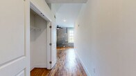 Located at 410 Court Street in Lynchburg, Virginia, this one-bedroom, one-bathroom unit offers a compelling mix of historic industrial character and contemporary finishes. Rich hardwood floors run throughout, complemented by crisp white walls and exposed original brick that lends the space a distinctive, loft-like ambiance.

The kitchen is a standout feature, showcasing bold granite countertops with dramatic veining, light maple cabinetry, a subway tile backsplash, stainless steel appliances, and a central island with a built-in sink. Pendant lighting and large windows flood the space with natural light, while the exposed brick wall adds raw texture alongside the modern finishes.

The spacious bedroom features original hardwood flooring, a ceiling fan, and exposed structural beams that echo the building's history. A hallway with a built-in closet connects the main living areas with practicality and ease.

The bathroom is cleanly finished with tile flooring, a tub-shower combination enclosed in glass, a warm wood vanity, and white countertops. Throughout the unit, high ceilings and an open layout contribute to a sense of generous space, making this Lynchburg residence a distinctive blend of heritage and modern comfort.