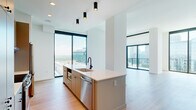 Located in Atlanta's vibrant Midtown neighborhood, this contemporary 3-bedroom, 4-bathroom residence offers a sleek, modern design throughout. Light-toned hardwood flooring flows seamlessly across the entire single-floor layout, complementing the clean white walls and minimalist aesthetic.

The open-concept kitchen and living area serves as the heart of the home, featuring a large center island with a white quartz countertop, a matte black faucet, and stainless steel appliances including a dishwasher and refrigerator. Warm taupe cabinetry lines the kitchen walls, while track pendant lighting adds a modern touch. Floor-to-ceiling windows and sliding glass doors flood the living area with natural light and frame sweeping panoramic views of the Atlanta skyline and surrounding cityscape, with access to a private balcony.

Each of the three bedrooms is generously proportioned, with the primary suite offering a dedicated walk-in closet outfitted with custom shelving and drawers. The primary bathroom features marble-tiled flooring, a white quartz vanity, matte black fixtures, and a glass-enclosed shower with subway tile surround. Additional bathrooms maintain the same refined aesthetic with clean vanities and contemporary hardware.

Clean hallways with recessed lighting and gray-accented doors complete this thoughtfully designed urban residence.