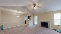The Bristol's 2-bedroom, 2-bathroom floor plan is thoughtfully designed on a single level, offering a comfortable and functional living environment. The spacious living room serves as the heart of the home, showcasing vaulted ceilings with a ceiling fan, a tile-surround fireplace, and plush carpeting. Natural light filters in through multiple windows and a glass-panel exterior door, creating a bright and welcoming atmosphere. A half-wall pass-through connects the living area to the kitchen, which features dark espresso cabinetry, granite-look countertops, tile flooring, and white appliances including a range, dishwasher, and refrigerator. A window above the sink allows for additional natural light. Both bedrooms are generously sized with soft carpeting, ceiling fans, and windows that bring in outdoor views and natural light. Each of the two full bathrooms is outfitted with tile flooring, dark wood vanities topped with granite-look counters, and shower-tub combinations with curtain enclosures. The neutral warm-toned palette throughout the home creates a cohesive and inviting ambiance, while the vaulted ceilings in the main living space add an airy sense of volume and openness.