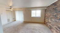 This single-floor residential unit offers a thoughtfully laid-out interior with a blend of classic and functional design elements. The living area serves as the heart of the space, showcasing a striking full-height exposed brick accent wall that adds warmth and character to the room. Plush wall-to-wall carpeting extends throughout, and vertical blinds on the sliding glass door and windows allow for adjustable natural light. The entry area transitions seamlessly from tile to carpet, providing a practical and welcoming introduction to the space.

The kitchen is efficiently designed with warm honey-toned wood cabinetry, stone-look countertops, a stainless steel sink, and white appliances including a range and over-the-range microwave, offering ample storage and workspace for everyday cooking.

The bedrooms are generously sized, each featuring soft carpeting, ceiling fans with integrated lighting, and vertical-blind-covered windows that bring in natural light. At least one bedroom includes a built-in closet with a hanging rod, providing practical storage solutions.

The bathroom is clean and functional, equipped with a shower-tub combination and crisp white surroundings. Throughout the unit, neutral tones and consistent finishes create a cohesive, move-in-ready atmosphere.