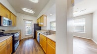 This 2-bedroom, 2-bathroom residence at The Cobblestone in El Cerrito, California offers a thoughtfully designed single-level layout with a cohesive mix of materials and finishes throughout. The kitchen is a functional galley-style space featuring warm honey-toned wood cabinetry with brushed nickel hardware, light stone-finish countertops, a double-basin sink, and stainless steel appliances including a refrigerator and dishwasher. Multiple windows bring in generous natural light and provide views of surrounding greenery, creating an inviting atmosphere for cooking and entertaining.

The two bedrooms offer a comfortable sense of scale, each featuring plush neutral carpeting and multiple windows fitted with horizontal blinds that allow for adjustable natural light and outdoor views. One bedroom benefits from a corner window configuration, further enhancing brightness and ventilation.

Both bathrooms maintain design consistency with the kitchen, showcasing matching wood cabinetry, stone-finish countertops, and brushed nickel fixtures. One bathroom includes a full tub-shower combination with white tile surround, while both feature wide vanity mirrors with stylish overhead lighting.

Wood-style flooring flows through the main living areas and bathrooms, providing visual continuity throughout the unit. The overall ambiance is clean, bright, and move-in ready.