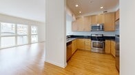 Located on Santa Monica Boulevard in the heart of Santa Monica, CA, this well-appointed one-bedroom, one-bathroom residence offers a thoughtfully designed single-floor layout. Light bamboo hardwood flooring runs throughout the open-concept living and kitchen area, creating a warm and cohesive feel. Large windows and a set of glass doors in the living room flood the space with natural light while offering views of the surrounding neighborhood and access to a private balcony.

The kitchen is efficiently designed with light maple cabinetry, dark granite countertops, and a full suite of stainless steel appliances including a gas range, built-in microwave, dishwasher, and refrigerator. Recessed lighting overhead adds a clean, modern touch. A dedicated hallway connects the main living area to the private spaces, and also houses a stacked in-unit washer and dryer for added convenience.

The bedroom is a comfortable retreat with plush carpeting, generous natural light from a window and glass door leading to a private balcony, and a full wall of mirrored sliding-door closets providing ample storage. The bathroom features tile flooring, a tub-shower combination with white subway tile surround, and a vanity with a granite countertop, maintaining a consistent design language throughout the home.
