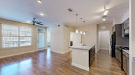 This thoughtfully designed one-bedroom, one-bathroom residence at 13555 Cullen Blvd in Houston, TX offers a comfortable and functional single-floor layout. The open-concept living and kitchen area is a standout feature, anchored by a granite-topped kitchen island with a built-in sink and pendant lighting overhead. The kitchen is equipped with dark-toned cabinetry, a subway tile backsplash, black appliances including a gas range and refrigerator, and a dedicated workspace with additional shelving. Track lighting and a ceiling fan enhance the bright, airy feel of the combined living and dining area, which benefits from natural light through slatted-blind windows. Hardwood-style flooring flows consistently throughout the main living spaces, adding warmth and cohesion. The bedroom is a comfortable size, featuring dual windows, a ceiling fan, and direct access to both the full bathroom and a walk-in closet outfitted with wire shelving. The bathroom includes a granite-topped vanity with dark cabinetry, tile flooring, and an adjacent walk-in closet. A dedicated laundry room houses a full-size washer and dryer with overhead wire shelving for added storage. The layout is efficient and well-organized, making excellent use of the available space.