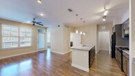 This thoughtfully designed one-bedroom, one-bathroom residence at 13555 Cullen Blvd in Houston, TX offers a comfortable and functional single-floor layout. The open-concept living and kitchen area is a standout feature, anchored by a granite-topped kitchen island with a built-in sink and pendant lighting overhead. The kitchen is equipped with dark-toned cabinetry, a subway tile backsplash, black appliances including a gas range and refrigerator, and a dedicated workspace with additional shelving. Track lighting and a ceiling fan enhance the bright, airy feel of the combined living and dining area, which benefits from natural light through slatted-blind windows. Hardwood-style flooring flows consistently throughout the main living spaces, adding warmth and cohesion. The bedroom is a comfortable size, featuring dual windows, a ceiling fan, and direct access to both the full bathroom and a walk-in closet outfitted with wire shelving. The bathroom includes a granite-topped vanity with dark cabinetry, tile flooring, and an adjacent walk-in closet. A dedicated laundry room houses a full-size washer and dryer with overhead wire shelving for added storage. The layout is efficient and well-organized, making excellent use of the available space.