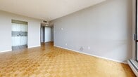 Located in the Lowertown neighbourhood of Ottawa, Ontario, this one-bedroom, one-bathroom unit offers a well-organized single-floor layout across a compact yet functional footprint. The living room is the standout space of the unit, featuring classic parquet wood flooring in a basket-weave pattern and floor-to-ceiling sliding glass doors that open to a balcony, flooding the room with natural light and offering expansive views of the surrounding cityscape and greenery. The neutral grey walls and white trim throughout the unit create a clean, cohesive aesthetic. The bedroom continues the parquet flooring and benefits from a large window that brings in generous natural light while providing additional outdoor views, complemented by a baseboard heating unit beneath the sill. The kitchen is efficiently designed in a U-shaped configuration, finished with white cabinetry, light tile countertops, and beige ceramic tile flooring. It is equipped with a white electric range and refrigerator, along with ample upper and lower cabinet storage. The bathroom is finished with tan ceramic tile flooring and includes a bathtub, toilet, and a vanity with a light countertop, accented by a chrome towel bar. Overall, the unit presents a bright, practical living space with consistent finishes throughout.