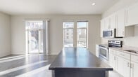 Located on N Commerce Street in Milwaukee, WI, this well-designed one-bedroom, one-bathroom unit offers a thoughtful layout across a single floor. The entrance opens into a corridor flanked by two closets, providing ample storage before leading into the main living area. Polished concrete floors run throughout the unit, lending an industrial-modern aesthetic that ties the spaces together cohesively. The combined kitchen and living room forms the heart of the home, bathed in natural light from tall windows and a sliding glass door. The kitchen is well-appointed with white shaker cabinetry, granite-look countertops, stainless steel appliances including a range, microwave, refrigerator, and dishwasher, and a central island that doubles as a prep and dining surface. Exposed ductwork along the ceiling adds an urban loft character to the space. The living area flows directly to a private balcony offering open views of the building's courtyard and the surrounding Milwaukee cityscape. The bedroom is a comfortable, dedicated space, while the bathroom features a full tub-shower combination. Recessed lighting throughout ensures a bright, clean atmosphere, making this unit a functional and stylish urban residence.