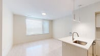 This well-appointed one-bedroom, one-bathroom residence at 39 Trotter Road in Weymouth, MA offers a thoughtfully designed open-concept floor plan with clean, modern finishes throughout. The combined living, dining, and kitchen area forms the heart of the home, featuring light-toned hardwood-style flooring that enhances the bright, airy atmosphere. The contemporary kitchen is equipped with stainless steel appliances — including a refrigerator, range, and dishwasher — flat-front cabinetry extending to the ceiling for ample storage, a tile backsplash, and a peninsula with an integrated sink and pendant lighting above, ideal for casual dining or meal prep. Large windows with roller shades allow natural light to fill the living and dining area. The bedroom offers a comfortable footprint with soft carpet flooring, two windows providing natural light, and access to two closets — including a walk-in closet outfitted with wire shelving and storage racks for organized living. The full bathroom features tile flooring, a walk-in shower with tile surround, a floating wood-toned vanity with a white countertop, and a large mirror. The residence presents a cohesive neutral palette and modern design sensibility throughout.
