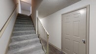 Located at 100 Antioch Pike in Nashville, TN, this three-bedroom, three-bathroom home spans three floors, offering a well-organized and functional layout. The entry level includes a garage and utility spaces, providing practical storage and parking solutions. Carpeted staircases with neutral-toned railings connect each floor, creating a cohesive flow throughout the home. The main living level features an open kitchen and living room combination, where the galley-style kitchen is equipped with taupe cabinetry, light stone countertops, black appliances, and wood-look flooring that extends into the living area. A peninsula countertop adds a natural division between the two spaces. The upper floor houses the three bedrooms, each featuring plush carpeting, ceiling fans with light fixtures, and windows that invite natural light and outdoor views. The spacious primary bedroom offers generous proportions and its own closet. The three bathrooms are clean and simply appointed, with wood-look flooring, light stone vanity countertops, and neutral cabinetry. An additional bonus room and dedicated laundry space add versatility to the home. Textured ceilings are consistent throughout, complementing the warm, neutral color palette found across all levels.