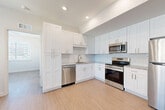 Located at 1002 Manatee Ave W in Bradenton, Florida, this thoughtfully designed 2-bedroom, 2-bathroom residence offers a clean, modern aesthetic throughout its single-floor layout. Light wood-look flooring flows seamlessly across every room, complemented by crisp white walls and recessed lighting that create a bright, airy atmosphere.

The open-concept living and dining area provides a comfortable sense of space, with natural light filtering in through blinds-fitted windows. The kitchen is a standout feature, showcasing white shaker-style cabinetry extending to the ceiling for ample storage, granite countertops, a subway tile backsplash, and a full suite of stainless steel appliances including a refrigerator, range, microwave, and dishwasher.

Both bedrooms are well-proportioned and feature light-filled windows with blinds and ceiling fans for added comfort. The primary bedroom is generously sized and includes a walk-in closet outfitted with wire shelving systems, while an additional closet provides further storage. A second closet with louvered doors adds to the unit's practical storage options.

The bathrooms are finished with elegant marble-look tile surrounds and soaking tubs with brushed nickel fixtures, adding a touch of luxury. A connecting hallway ties the layout together efficiently, making this a well-organized and polished residence.