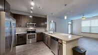 Located at 645 Old Hickory Boulevard in Nashville, Tennessee, this well-appointed two-bedroom, two-bathroom residence offers a thoughtfully designed single-floor layout. The open-concept kitchen is a standout feature, showcasing dark espresso cabinetry, granite countertops, a subway tile backsplash, stainless steel appliances including a refrigerator, range, microwave, and dishwasher, and a peninsula with pendant lighting that flows seamlessly into the living area. The living room features durable wood-style flooring, a ceiling fan, and a full-light entry door that invites natural light into the space. Both bedrooms are carpeted for comfort, equipped with ceiling fans, and offer ample natural light through blinded windows. The primary bedroom connects directly to its private en-suite bathroom, which includes a granite-topped vanity with dark cabinetry, a soaking tub with white subway tile surround, and access to a spacious walk-in closet with wire shelving. The second bathroom mirrors the same quality finishes. A second walk-in closet provides additional storage. Wood-style flooring runs throughout the main living areas, lending a cohesive and modern aesthetic to this move-in-ready Nashville home.