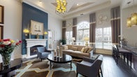 This single-story clubhouse is designed to impress, offering a sophisticated gathering space with a carefully curated interior that balances comfort and elegance. The main lounge area is defined by soaring ceilings and a coffered tray ceiling detail overhead, from which a striking multi-bulb chandelier with gold-toned accents is suspended. Large arched and double-hung windows flood the space with natural light, framed by layered brown and cream drapery panels that add texture and warmth.

A bold teal accent wall provides a dramatic backdrop for the white-mantled fireplace, which serves as a central focal point in the lounge. The surrounding seating arrangement includes a neutral linen sofa with decorative throw pillows, patterned accent chairs, and a dark round coffee table anchored by a geometric-patterned area rug in blue, gold, and gray tones. Wall sconces, framed artwork, and decorative plate arrangements contribute to the polished, gallery-like atmosphere throughout.

An adjacent kitchenette features dark espresso cabinetry, granite countertops, hardwood-style flooring, a mosaic tile backsplash, and recessed lighting—well-equipped to support community events and gatherings. The entry area showcases a marble-inlaid tile floor, adding a grand first impression to this thoughtfully appointed clubhouse.