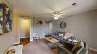 Located at 3500 Beaver Place Rd in Lexington, Kentucky, this single-floor residence offers a well-organized layout designed for comfortable everyday living. The living room serves as the heart of the home, finished with neutral gray walls, carpet flooring, and a ceiling fan with light fixture. A sunburst mirror adds a decorative focal point, while a sliding glass door fills the seating area with natural light and provides direct access to an outdoor patio. The kitchen is outfitted with dark cabinetry, white quartz-style countertops, a classic white subway tile backsplash, and black stainless steel appliances including a range, microwave, and refrigerator — all set over durable wood-style flooring. The two bedrooms offer carpeted floors, neutral wall tones, and ample room for furnishings. One bedroom benefits from a window with natural light and includes generous dresser space, while the other features warm ambient lighting and access to an adjoining room. The full bathroom includes a tub/shower combination, wood-style flooring, a vanity with a marble-style countertop, and a medicine cabinet mirror. The home's cohesive neutral palette and practical layout make it a functional and inviting space throughout.