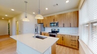 This thoughtfully designed single-floor unit blends modern aesthetics with functional living. Light hardwood flooring flows seamlessly throughout, connecting each space with a cohesive and contemporary feel.

The kitchen serves as the heart of the unit, showcasing warm wood cabinetry with sleek black hardware, a white quartz island with an undermount sink, and a full suite of stainless steel appliances including a refrigerator with ice maker, electric range, microwave, and dishwasher. White subway tile backsplash adds a clean, classic contrast, while pendant lighting above the island creates an inviting atmosphere. Large windows bathe the kitchen in natural light and offer views of the surrounding urban landscape.

The living areas are bright and open, with generous windows framing city views and allowing abundant natural light to fill the rooms. A stylish sliding barn door adds a modern touch between spaces. The spacious walk-in closet features wire shelving on multiple levels, providing ample organized storage.

The bathroom is elegantly finished with full subway tile surrounding the shower-tub combination, a glass enclosure with matte black hardware, a white quartz vanity with an undermount sink, and a large mirror. The hallway connects the rooms efficiently, with louvered closet doors adding texture and practicality to the clean white walls.