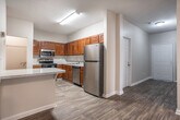Located at 1205 Maple St in Carrollton, Georgia, this single-floor residence offers a thoughtfully laid-out interior finished with warm, neutral tones throughout. The living area is bright and open, featuring wood-look flooring, a ceiling fan with recessed lighting, and a glass door that welcomes natural light and outdoor views. The kitchen is well-appointed with rich, warm-toned wood cabinetry, light speckled countertops, and a full suite of stainless steel appliances including a range, over-the-range microwave, dishwasher, and refrigerator. Wood-look flooring continues seamlessly through this space, adding to the cohesive aesthetic. The bedrooms are carpeted for comfort, with each room offering natural light through slatted blinds. One bedroom includes built-in shelving and a built-in desk, making it well-suited as a home office or study. A closet with classic six-panel doors is also present. The primary bedroom connects directly to a private bathroom. Two bathrooms serve the residence; one features a tub-shower combination with chrome fixtures, a vanity with white cabinetry, and wood-look flooring. The second bathroom is similarly finished and includes a towel bar and vanity area. The overall ambiance is clean, functional, and move-in ready.