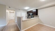 Located in Columbus, Ohio, this single-floor, 2-bedroom, 2-bathroom home offers a thoughtfully designed layout with modern finishes throughout. The open-concept kitchen and dining area serves as the heart of the home, featuring a peninsula with granite-style countertops, an undermount sink, dark espresso cabinetry with open shelving, a tile backsplash, and stainless steel appliances. Light wood-tone flooring runs through the main living areas, creating a clean and cohesive aesthetic. The living room is bright and spacious, anchored by a sliding glass door that opens to a private patio with outdoor views of lush greenery. Both bedrooms are carpeted and filled with natural light from large windows. The generously sized primary bedroom includes a walk-in closet with wire shelving for ample storage. Each bathroom is finished with dark wood vanities, white countertops, and wood-look tile flooring; one features a walk-in glass-enclosed shower. A dedicated laundry area and pantry add everyday convenience. A central hallway connects all rooms efficiently, with a smart thermostat panel for climate control. The neutral color palette and consistent finishes throughout give the space a polished, move-in-ready feel.