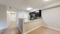 Located in Columbus, Ohio, this single-floor, 2-bedroom, 2-bathroom home offers a thoughtfully designed layout with modern finishes throughout. The open-concept kitchen and dining area serves as the heart of the home, featuring a peninsula with granite-style countertops, an undermount sink, dark espresso cabinetry with open shelving, a tile backsplash, and stainless steel appliances. Light wood-tone flooring runs through the main living areas, creating a clean and cohesive aesthetic. The living room is bright and spacious, anchored by a sliding glass door that opens to a private patio with outdoor views of lush greenery. Both bedrooms are carpeted and filled with natural light from large windows. The generously sized primary bedroom includes a walk-in closet with wire shelving for ample storage. Each bathroom is finished with dark wood vanities, white countertops, and wood-look tile flooring; one features a walk-in glass-enclosed shower. A dedicated laundry area and pantry add everyday convenience. A central hallway connects all rooms efficiently, with a smart thermostat panel for climate control. The neutral color palette and consistent finishes throughout give the space a polished, move-in-ready feel.