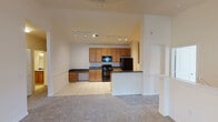 This single-floor residence offers a thoughtfully designed layout that balances functionality and comfort throughout. The open-concept living and kitchen area serves as the heart of the home, where warm-toned carpet in the living space transitions seamlessly to light ceramic tile flooring in the kitchen. The kitchen is well-equipped with honey-toned wood cabinetry, dark granite-style countertops, black appliances including a range, built-in microwave, and refrigerator, along with a double sink and a convenient breakfast bar that defines the boundary between the two spaces. Track lighting illuminates both areas effectively. The living area features vaulted ceilings that enhance the sense of openness, with a glass door providing access to the outdoors and allowing natural light to fill the room. The bedrooms are carpeted and generously sized, each fitted with ceiling fans and windows dressed with blinds that offer views of the surrounding greenery. The bathrooms are finished with tile flooring, wood vanities topped with dark granite-style counters, large mirrors, and full tub-shower combinations with tiled surrounds. Clean, neutral wall tones throughout the residence create a versatile backdrop that suits a variety of interior styles.