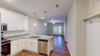 Located at 4650 Crescent Pointe Dr in North Charleston, SC, this single-story residence offers a well-designed, open-concept layout that seamlessly connects the kitchen and living areas. The kitchen is a standout feature, equipped with crisp white shaker cabinetry, granite countertops, a peninsula with a built-in sink and pendant lighting overhead, and a full suite of stainless steel appliances including a refrigerator, range, microwave, and dishwasher. Warm hardwood flooring flows throughout the main living spaces, adding character and continuity to the open floor plan. The living area benefits from natural light admitted through French doors and a ceiling fan overhead, creating a comfortable and airy atmosphere. Bedrooms are carpeted for added comfort and each include ceiling fans and windows with natural light. One bedroom features a dedicated walk-in closet with wire shelving, providing generous storage. The bathroom is outfitted with a full tub-shower combination set against clean white tile surround and brushed nickel fixtures. A dedicated laundry room with full-size washer and dryer hookups and overhead wire shelving adds everyday convenience to this functional and inviting home.