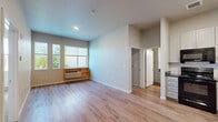 Located at 5050 Morrison Rd in Denver, Colorado, this three-bedroom, one-bathroom residence offers a practical and well-designed single-floor layout. The combined kitchen and living area serves as the heart of the home, featuring light wood-tone flooring that extends throughout the main living spaces. The kitchen is outfitted with white shaker-style cabinetry, a herringbone tile backsplash, dark countertops, and a full suite of black appliances including an electric range, microwave, dishwasher, and refrigerator. Large windows in the living area invite natural light and provide views of surrounding greenery, contributing to a bright and welcoming atmosphere. The three bedrooms are finished with plush carpeting and neutral-toned walls, offering a comfortable and quiet retreat. At least one bedroom features a walk-in closet with built-in shelving, while others are served by a ceiling fan. The shared full bathroom includes a tub and shower combination with clean white fixtures and wood-look flooring. A hallway connects the private areas of the home, ensuring a logical and functional flow throughout. The overall design emphasizes clean lines, neutral finishes, and practical amenities suited for everyday living.