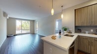 Located at 1091 W El Camino Real in Sunnyvale, California, this single-floor residence offers a thoughtfully designed layout with modern finishes and an abundance of natural light. The open-concept living and kitchen area serves as the heart of the home, showcasing rich dark hardwood flooring, neutral-toned walls, and large sliding glass doors that frame views of mature trees and the outdoors. Pendant lighting with warm tones illuminates the kitchen island, which features a white quartz countertop and an integrated sink. The kitchen is fully equipped with stainless steel appliances, including a range, microwave, and refrigerator, complemented by floor-to-ceiling wood-grain cabinetry offering generous storage. The bedrooms are carpeted for comfort and benefit from multiple windows that invite natural light and garden views. A wall-mounted mini-split HVAC unit ensures year-round climate control. The bathroom includes a floating wood-grain vanity with a white quartz countertop, a large mirror, and a full tub-shower combination with white tile surround. Throughout, the design balances a clean, contemporary aesthetic with warm, natural materials, creating a comfortable and functional living environment in the heart of Sunnyvale.