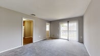 This single-floor residence offers a practical and well-organized layout designed to maximize comfort and usability. The living area is generously sized, finished with soft grey carpeting, and painted in neutral grey tones throughout. A sliding glass door with vertical blinds opens directly onto a balcony, allowing natural light to fill the space and providing outdoor views of the surrounding area. An additional window further brightens the room.

The kitchen is equipped with warm-toned wooden cabinetry offering ample storage across both upper and lower units. Laminate countertops, a double-basin sink, a gas range with overhead ventilation, and a full-size refrigerator complete the functional setup. Wood-look flooring runs through the kitchen, adding a clean contrast to the carpeted living spaces.

The bedrooms are comfortably sized, each carpeted and painted in soft neutral tones. Windows fitted with horizontal blinds provide natural light and privacy. At least one bedroom features a built-in closet with bi-fold doors. The bathroom includes a full tub and shower combination, a vanity with white cabinetry, and wood-look flooring, maintaining the clean aesthetic found throughout the unit.