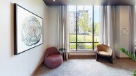 Located at 412 Summer St in Abington, Massachusetts, this single-floor space offers a well-appointed layout across a compact but efficiently utilized footprint. The hallway entry features glass-paneled doors that invite natural light in while providing a clear sightline to a warm reception area finished in rich wood tones and large-format tile flooring, setting a polished and professional tone from the moment of arrival.

The living room is a standout area, anchored by a large floor-to-ceiling window that frames sweeping views of a lush green lawn and surrounding buildings. Neutral-toned carpet, elegant draping curtains, and contemporary seating create a comfortable and inviting atmosphere bathed in natural light.

Among the additional rooms, a private nook or workspace features dramatic stone-look wall panels with flowing, marble-like veining in soft creams and warm taupes, complemented by a clean white built-in desk surface and upholstered seating — ideal for focused work or quiet reflection.

Two bathrooms round out the layout, contributing to the space's practical functionality. Throughout, the design blends modern finishes — including warm wood accents, plush carpeting, and refined stonework — to create a cohesive, sophisticated ambiance suited for both comfort and purposeful use.