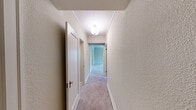 Located at 1220 Boren Ave in Seattle's First Hill neighborhood, this two-bedroom, one-bathroom unit offers a functional and well-appointed single-floor layout. The spacious primary bedroom is a standout feature, with soft carpet flooring, crown molding, and multiple windows that frame views of the surrounding tree canopy, filling the room with natural light. The second bedroom is similarly carpeted and benefits from a window with a classic blind, along with access to a closet and hallway connecting to the main living areas. The kitchen is accessed through a charming arched entryway and features white shaker-style cabinetry, a stainless steel refrigerator, a gas range, tile flooring, and an in-unit washer — offering both style and practicality. A second kitchen or utility area provides additional counter space and a stainless steel sink. The bathroom is clean and bright, appointed with large white subway tile surrounding a full tub-shower combination with chrome fixtures. Throughout the unit, crown molding and neutral warm-toned walls create a cohesive and inviting atmosphere. Two closets and two hallways provide ample storage and easy circulation throughout the home.