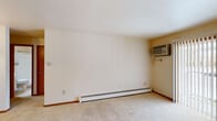 Located in Grand Rapids, MI, this one-bedroom, one-bathroom unit offers a functional and straightforward layout across a single floor. The living room is a comfortable, carpeted space featuring baseboard heating, a wall-mounted air conditioning unit, and a sliding glass door fitted with vertical blinds that opens to an outdoor view, allowing natural light to filter in. The galley-style kitchen is efficiently designed with rich wood cabinetry lining both walls, light-toned countertops, a stainless steel sink, a white electric range, and a refrigerator. Tile flooring and overhead lighting complete the practical kitchen setup. The bedroom offers plush carpeting, a window that brings in natural light, and a built-in closet with shelving and hanging rods, providing ample storage. Baseboard heating is also present in the bedroom for year-round comfort. The bathroom is clean and well-appointed, featuring a full tub-shower combination with brushed nickel fixtures and a grab bar, a toilet, a vanity, and an overhead storage cabinet. Warm wood-toned doors and trim are consistent throughout the unit, contributing to a cohesive and tidy interior aesthetic.