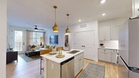 Located at 382 Red Bud Circle in Hendersonville, NC, this thoughtfully designed single-floor home offers 2 bedrooms and 3 bathrooms within a well-organized layout. The open-concept living, dining, and kitchen area serves as the heart of the home, where light hardwood floors and white walls create a bright, welcoming atmosphere. The kitchen is equipped with shaker-style cabinetry in a soft gray-white finish, white quartz countertops, a subway tile backsplash, stainless steel appliances, and a central island with a sink and pendant lighting in brushed gold. The living room benefits from natural light streaming through large windows and a glass door that opens to an outdoor balcony. The adjacent dining area provides an intimate space with clean, modern styling. The spacious primary bedroom features plush carpeting, a ceiling fan, and a dedicated walk-in closet with wire shelving. The second bedroom is comfortably sized with similar finishes and wall-mounted décor. The bathrooms are finished with gray shaker vanities, white countertops, and light wood-style flooring, with at least one bathroom featuring a tub-shower combination. The home's clean, neutral palette and consistent use of black hardware throughout lend a cohesive, contemporary feel.