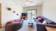 This two-bedroom, two-bathroom residence in Ames, Iowa offers a well-organized single-floor layout designed for comfortable everyday living. The living room serves as the heart of the home, featuring carpet flooring, a ceiling fan, and a sliding glass door that opens to a private balcony with outdoor views — bringing in natural light and a sense of openness. The galley-style kitchen is outfitted with warm honey-toned wood cabinetry, granite-look countertops, black appliances including an electric range and refrigerator, and durable hardwood-style flooring, providing ample storage and prep space. Both bedrooms are carpeted and offer generous room proportions, with the primary bedroom benefiting from its own en-suite bathroom and a large walk-in closet with built-in shelving and hanging rods. The second bedroom is well-sized with easy access to the second full bathroom. Each bathroom features tile flooring and warm wood vanities with sizeable countertops. A dedicated in-unit laundry room with side-by-side washer and dryer adds everyday convenience. Two closets throughout the unit provide substantial storage capacity, rounding out a practical and functional floor plan suited for a variety of lifestyles.