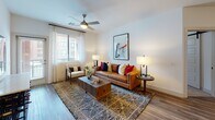 This single-floor residence offers a well-designed open layout that seamlessly connects its main living areas. The living room is bright and inviting, featuring wood-look flooring, a ceiling fan, and a window dressed with sheer curtains that allow natural light to fill the space comfortably.

The kitchen is a standout feature, finished with dark wood-grain cabinetry, stainless steel appliances, a subway tile backsplash, and crisp white quartz countertops. A peninsula with pendant lighting overhead provides additional seating with modern black chairs, making it ideal for casual dining or entertaining.

Multiple bedrooms are present throughout the residence, each outfitted with plush carpeting, ceiling fans, and windows with blinds. The bedrooms vary slightly in configuration, offering flexibility for different uses, and each maintains a clean, neutral palette that lends a calm atmosphere.

The bathrooms are well-appointed, featuring wood-look tile flooring, dark vanity cabinetry with white countertops, and glass-enclosed walk-in showers with large-format tile. One bathroom includes a stylish barn door that leads to a dedicated walk-in closet, adding both a functional and design-forward element.

Overall, the residence presents a cohesive modern aesthetic with consistent finishes, ample natural light, and thoughtful details throughout each room.