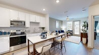 This well-designed single-floor residence offers a thoughtfully laid-out open-concept floor plan that seamlessly connects the kitchen, dining, and living areas. The kitchen is a standout, outfitted with crisp white cabinetry, granite countertops, a classic subway tile backsplash, and a full suite of stainless steel appliances including a refrigerator, electric range, microwave, and dishwasher. A central island with bar seating provides an ideal casual dining space. The living area is bright and inviting, featuring warm-toned walls, wood-look flooring, and a ceiling fan that complements the natural light streaming in through large windows. A private door off the living space opens to outdoor views, adding an airy quality to the room. The bedroom is carpeted and generously sized, with ample natural light, a ceiling fan, and easy access to a full bathroom. The bathroom features white cabinetry, granite countertops, and wood-look flooring. A dedicated in-unit laundry area with a full-size washer and dryer adds everyday convenience. Throughout the residence, neutral tones, modern finishes, and quality materials create a clean, contemporary aesthetic that is both functional and welcoming.