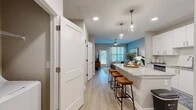 Located at 1880 SW 43rd St in Gainesville, FL, this one-bedroom, one-bathroom residence offers a thoughtfully designed open-concept layout with modern finishes throughout. Light wood-style flooring flows through the main living areas, creating a cohesive and inviting atmosphere.

The kitchen is a standout feature, showcasing crisp white shaker cabinetry, subway tile backsplash, granite countertops, and a full suite of stainless steel appliances, including a range, microwave, dishwasher, and refrigerator. A spacious island with seating provides additional prep space and serves as a natural gathering point between the kitchen and living area. Pendant lighting adds a stylish touch overhead.

The combined kitchen and living area is bright and open, with a sliding glass door and large windows that invite natural light and provide outdoor views. The living space is accented by a soothing blue-gray feature wall that carries through into the bedroom.

The bedroom is comfortably sized with plush carpeting, large windows, and a bold teal accent wall that adds character and warmth. A dedicated closet provides convenient storage.

The bathroom features granite countertops, a full tub-shower combination with white tile surround, and warm neutral tones. The overall ambiance is modern, clean, and comfortable.