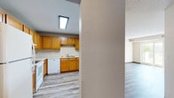 This single-floor, 2-bedroom, 1-bathroom residence offers a practical and comfortable layout across a compact but efficient footprint. The open-concept kitchen and living area serves as the heart of the home, with the kitchen featuring warm oak cabinetry, light countertops, a double-basin sink, and white appliances including a range, dishwasher, and full-size refrigerator. Light wood-style vinyl flooring flows throughout the main living areas, adding a clean, cohesive look. The living area connects directly to a private balcony through a sliding glass door, bringing in natural light and pleasant outdoor views of surrounding greenery. The primary bedroom is a comfortable size with carpeted flooring, a window overlooking the outdoors, and a generous closet with double doors. The second bedroom also features carpet and offers versatility as a guest room or home office. The full bathroom includes a wide vanity with an oak cabinet base, solid-surface countertop, and large mirror. A dedicated in-unit laundry room accommodates a full-size washer and dryer. A central hallway ties the layout together efficiently. Textured ceilings are found throughout, and dark baseboards provide a grounding contrast to the neutral wall tones.